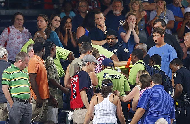 Rescue workers carry an injured fan from the stands at Turner Field during a baseball game between Atlanta Braves and New York Yankees, Saturday, Aug. 29, 2015, in Atlanta. The fan fell from the upper deck into the lower-level stands and was given emergency medical treatment before being taken to a hospital where he was pronounced dead. 