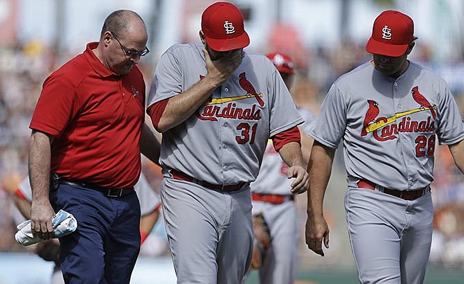 St. Louis Cardinals pitcher Lance Lynn (31) walks off the field with a trainer, left, and manager Mike Matheny, right, after injuring himself while throwing to first base in the eighth inning of a baseball game against the San Francisco Giants, Saturday, Aug. 29, 2015, in San Francisco. 
