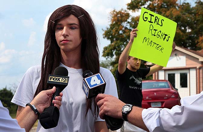 In a Monday, Aug. 31, 2015 photo, Lila Perry, a Hillsboro High School senior and transgender student, speaks with reporters as Blayke Childs, back, offers his opinion after a student walkout at Hillsboro High School over Perry's request to use the girls bathrooms and locker rooms rather than a unisex faculty bathroom. (Robert Cohen/St. Louis Post-Dispatch via AP)