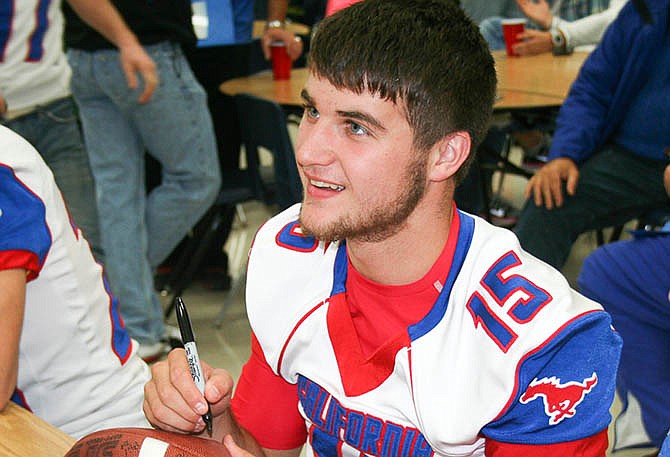 In this Nov. 20, 2014 file photo, Jaden Barr, then a high school senior, signs a football for one of his fans during a California Pintos' meet-and-greet with community members.