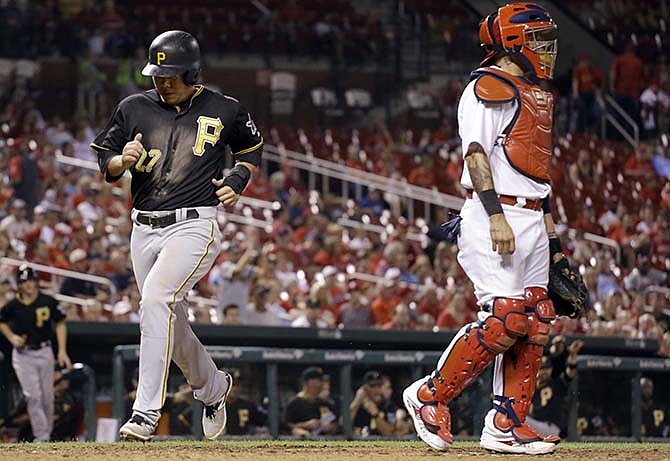 Pittsburgh Pirates' Jung Ho Kang, left, scores past St. Louis Cardinals catcher Yadier Molina on single by Jordy Mercer during the ninth inning of a baseball game Friday, Sept. 4, 2015, in St. Louis.
