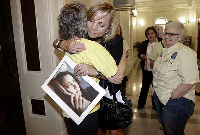 In this Sept. 9, 2015, file photo, Debbie Ziegler holds a photo of her daughter, Brittany Maynard, as she receives congratulations from Ellen Pontac, after a right-to die measure was approved by the Assembly in Sacramento, Calif. Maynard was a 29-year-old California woman with brain cancer who moved to Oregon to legally end her life. California lawmakers gave final approval Friday, Sept. 11, to a bill that would allow terminally ill patients to legally end their lives. The measure faces an uncertain future with Gov. Jerry Brown, a former Jesuit seminarian who has not said whether he will sign it. 