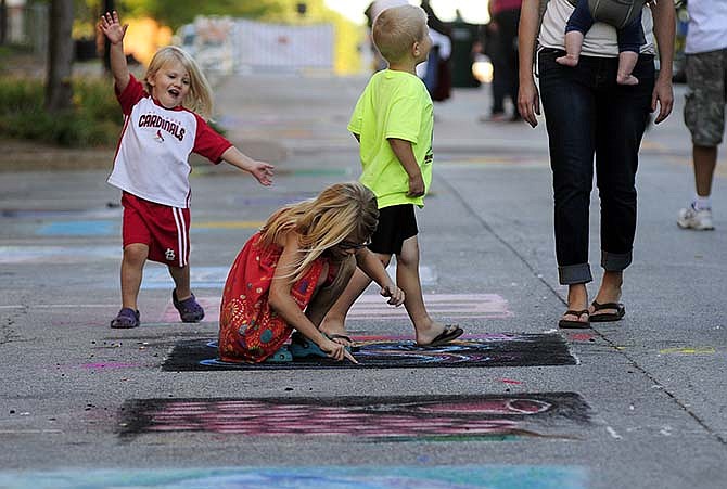 Siblings, from left, Kinsley, Riley and Colt Berendzen check out some of the street chalk artwork
on display as they and their parents Jeff and Jodi Berendzen make their way down Jefferson City's High Street
during the 24th annual Capital Jazzfest and Street Art Fair on Saturday.