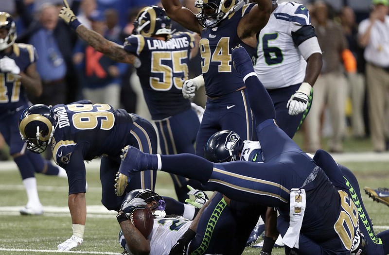 Seahawks running back Marshawn Lynch lays on his back after being stopped on the final play of overtime on Sunday, in St. Louis. Celebrating for the Rams are (from left) Aaron Donald, James Laurinaitis, Robert Quinn and Michael Brockers.