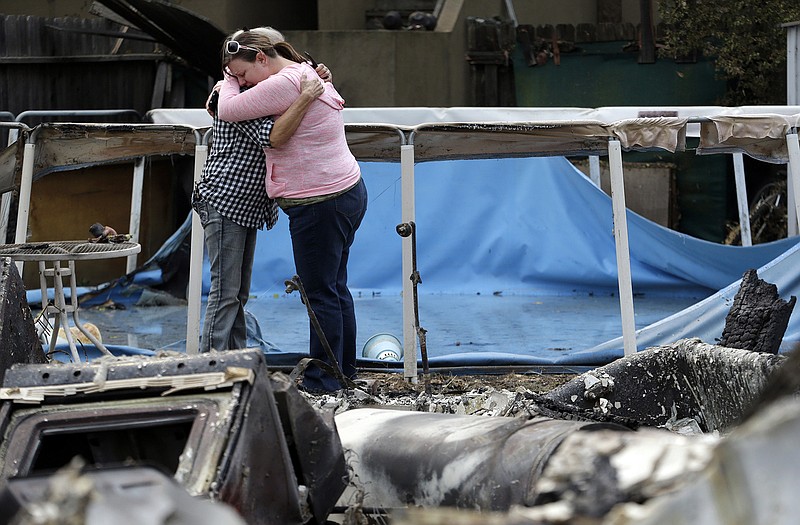 Deanna Hingst, right, embraces her mother Shirley Leuzinger as they stand at the family's destroyed home Monday in Middletown, Calif. Two of California's fastest-burning wildfires in decades overtook several Northern California towns, killing at least one person and destroying hundreds of homes and businesses and sending thousands of residents fleeing highways lined with buildings, guardrails and cars still in flames.