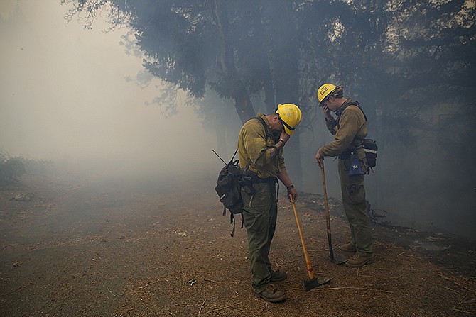 Napa Strike Team firefighters Mike Holmes and Dan Stith cover their eyes from the smoke during a controlled burn on Monday in Adams, California. 