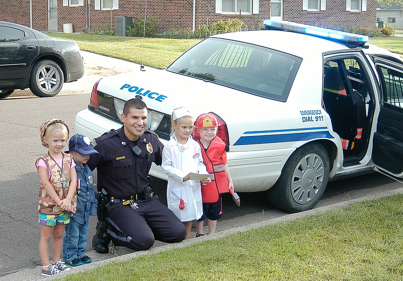 At "Lil Tots", Officer Rafael Ayala with children dressed for "Heroes Day" as military, police, medical and firefighter - representing those who responded to the Twin Towers after the 9/11 attack in 2001.