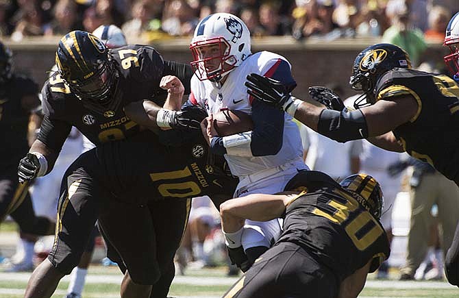 Connecticut quarterback Bryant Shirreffs, center, is gang tackled by Missouri's Rickey Hatley, right, Josh Augusta, left, Michael Scherer (30) and Kentrell Brothers (10) during the fourth quarter of an NCAA college football game Saturday, Sept. 19, 2015, in Columbia, Mo. Missouri won the game 9-6.