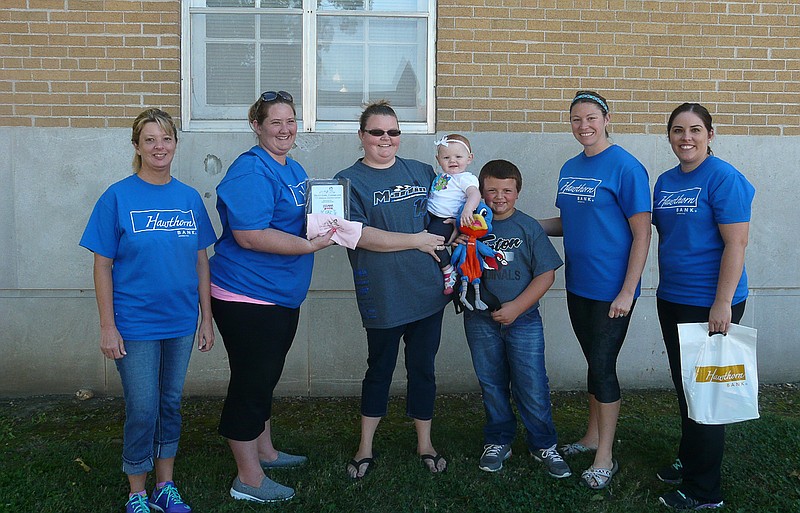 Skii Cary, daughter of Tracy and Nathan Cary, Tipton, was the winner of the girls division of the 2015 Ozark Ham and Turkey Diaper Derby. She is being held by mother Tracy with brother Walker standing beside them. She was presented her first place plaque, Best Girl Crawler onsie and other prizes by Kendra Fischer, Jenny Brown, Becky Lawson and Nicole Dicus of Hawthorn Bank.