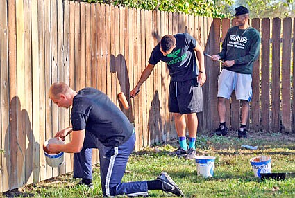 Members of the William Woods basketball team apply stain to the fence outside the Coalition Against Rape and Domestic Violence Wednesday. Members of the basketball team joined the Fulton Rotary Club and the Heartland Church of the Nazarene Youth Group to give the CARDV facilities a face-lift.