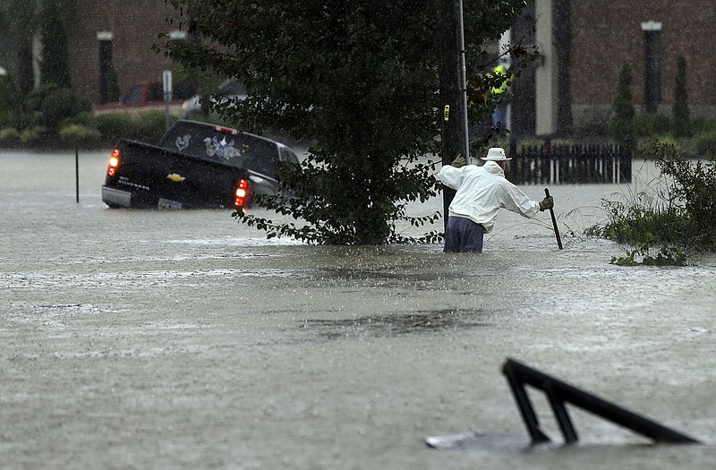 A vehicle and a man try to navigate floodwaters in Florence, S.C., Sundya as heavy rain continues to cause widespread flooding in many areas of the state. The rainstorm drenching the East Coast brought more misery to South Carolina, cutting power to thousands, forcing hundreds of water rescues and closing scores of roads because of floodwaters.