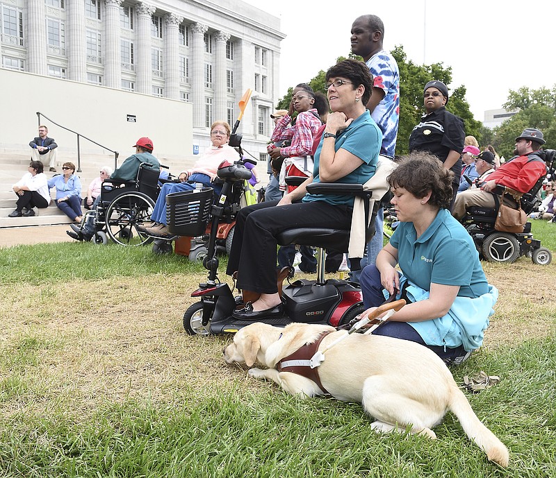 Japan rests easy on the Capitol lawn as she lays by her handler, Stephanie McDowell. McDowell and Diana Wieland, on scooter, are both from Paraquad, an independent living resource center in St. Louis. Both were at the Capitol in celebration of 25 years of the Americans with Disability Act (ADA) and Missouri Disability History and Awareness Month. The Governor's Council on Disability hosted the event Tuesday. Representatives from independent living centers were on hand to hear speakers talk about the importance of the ADA.
