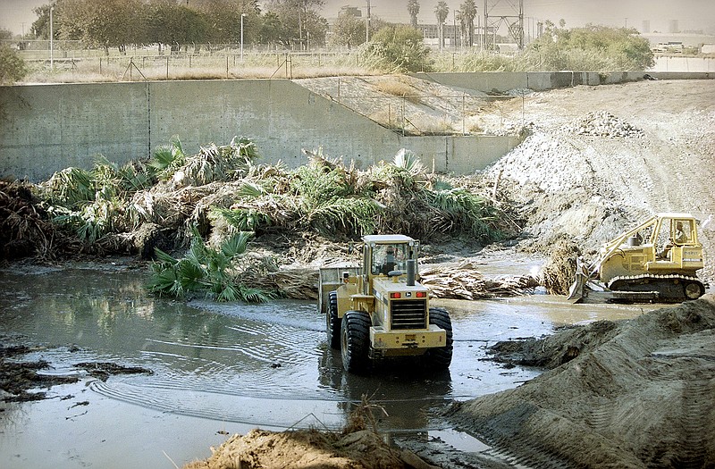 Bulldozers scoop up debris, including downed palm trees, along the Los Angels river bed, in Glendale, Calif., in preparations for El Nino in the late 1990as. 
