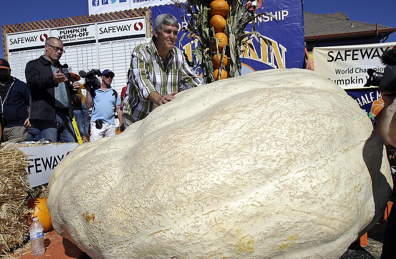Steve Daletas, center, of Pleasant Hill, Ore. poses for photos with his his pumpkin, which weighed in at 1969 pounds to win the Annual Safeway World Championship Pumpkin Weigh-Off Monday in Half Moon Bay, Calif. 