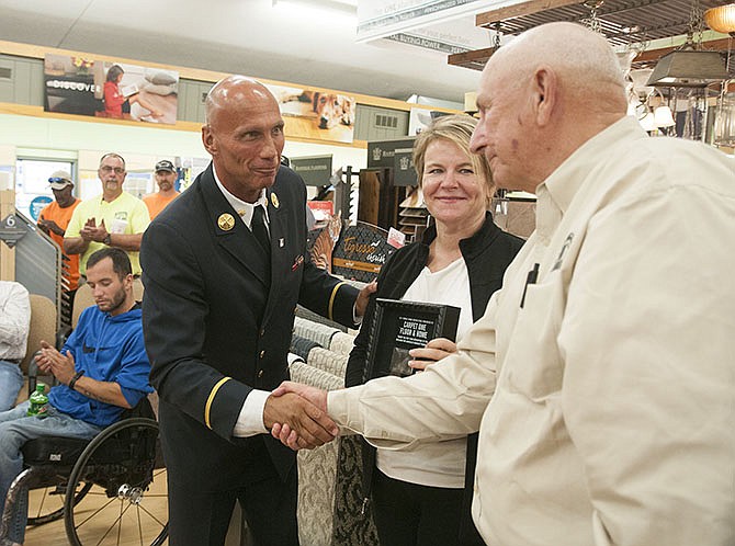 Jack Oehm, left, a retired New York City firefighter, shakes the hand of Bob Scruggs, former president of Scruggs Lumber, on Thursday inside the company's building after giving Scruggs and his daughter Stephanie Scruggs, the current president, a piece of the 9/11 World Trade Center. Scruggs helped in securing a smart home for a Jefferson City veteran paralyzed in Afghanistan after 9/11.