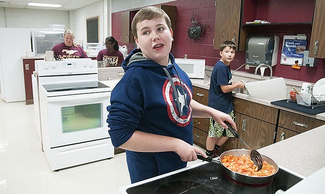 Lane Russell, an eighth-grade student at Eldon Middle School, talks to his
teacher during an after school Family and Consumer Science class activity.
Students in the class created pizza sauce for mini-pizzas to serve to their
peers as a part of the school's mission to improve student health.