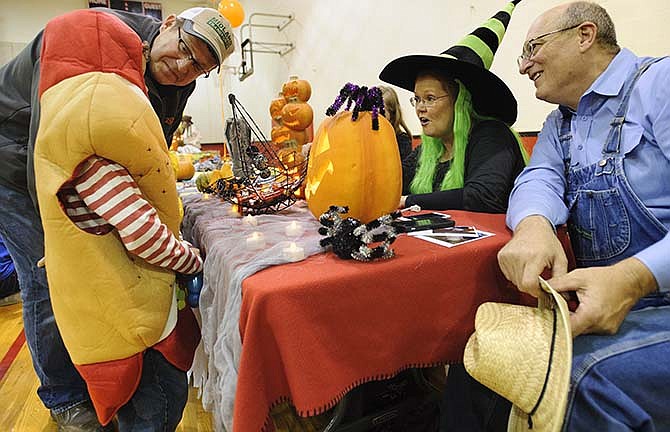 Steve Jacobek, left, listens as his hot dog son, Bergen Jacobek, tells a funny joke Saturday, Oct. 31, 2015 to First Christian Church volunteers Karen and Dan Davis as they man the joke table during First Baptist Church's trunk or treat event.