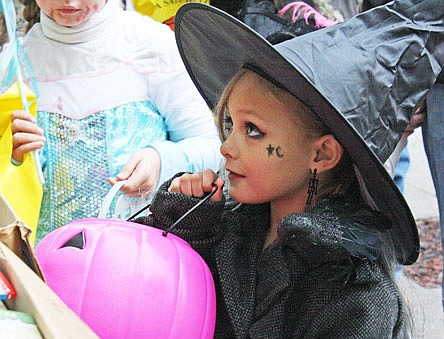 Emily Brown, 5, holds up her purple pumpkin to receive some candy during the Brick District trick-or-treat event Saturday afternoon. Despite an early morning rain, hundreds of children and parents arrived in downtown Fulton to participate in the festivities.