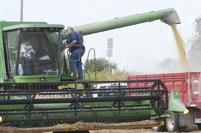 Harry Thompson climbs up a combine to talk to Carlene Bates as she empties the hopper into the grain truck Oct. 20, 2015 on a Thompson family farm near the Jefferson City airport.