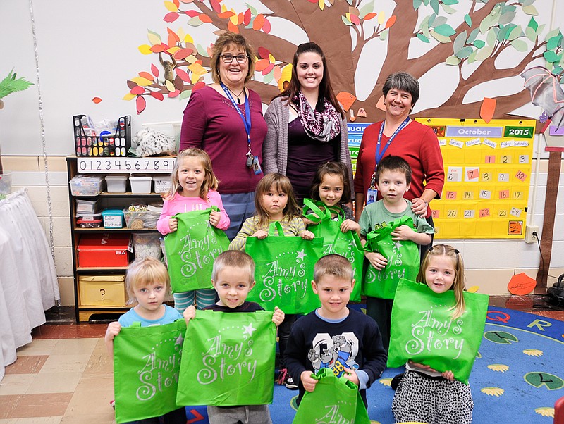 Russellville High School senior and A+ tutor Katie Ford, speech teacher Michelle Ford and pre-kindergarten teacher Ann Brennecke pose with part of the Russellville preK class, which received bags of books donated from Amy's Story.