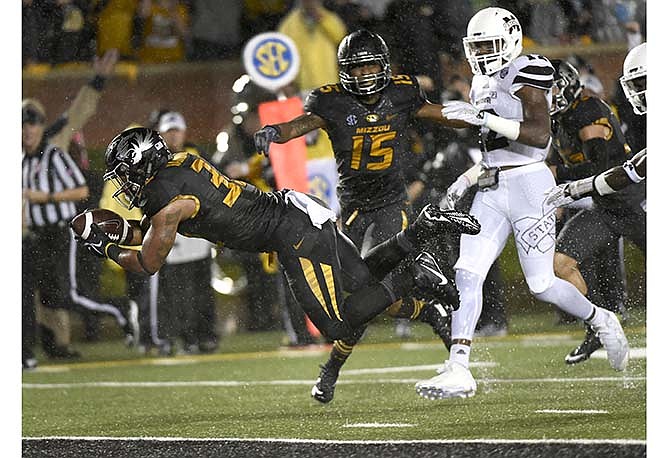 Missouri running back Russell Hansbrough, left, dives into the end zone for a touchdown past teammate linebacker Grant Jones, center, and Mississippi State defensive back Jamal Peters, right, during the first half of an NCAA college football game on Thursday, Nov. 5, 2015, in Columbia, Mo.