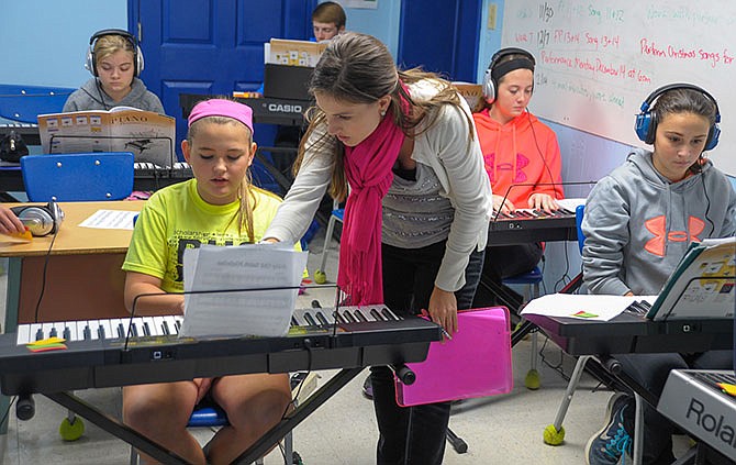 Second-year teacher Kristen Foster discusses a piece of music with Russellville seventh-grader Alex Metcalf during the middle school keyboarding class.