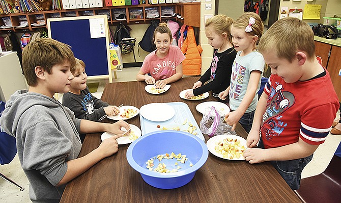 Callaway Hills kindergarteners and their fifth-grade mentors work together Friday morning to cut apples into very small pieces to go into the crockpot Monday to make apple butter. Seated clockwise, from left are: Clayton Drinkard, Dennis Miller, Kaylee Hiatte, Madison Gardner, Carly Bell and Trent Ford. Drinkard and Hiatte are fifth-grade mentors to the kindergarten students. Several students said they had not tasted apple butter before so were excited to give it a try.