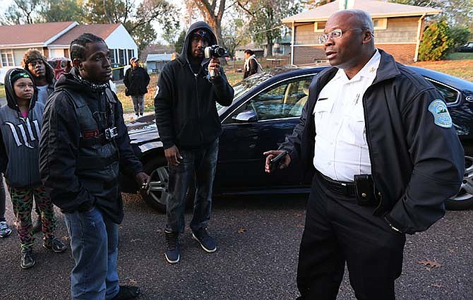 In this Oct. 28, 2015 file photo, Interim Ferguson, Mo., Police Chief Andre Anderson, right, talks with people in Normandy, Mo. The city of Ferguson announced Friday, Nov. 29, 2015, that Anderson is leaving a month earlier than expected. He was appointed to a six-month interim position in July, taking leave from his job with Glendale, Arizona, police, where he will return. (Chris Lee/St. Louis Post-Dispatch via AP, File)