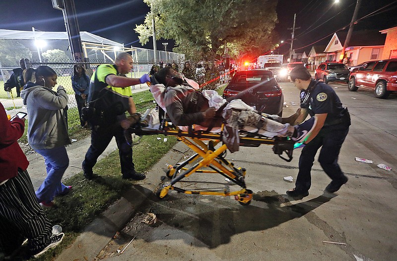Officials remove a man from the scene following a shooting in New Orleans on Sunday.
