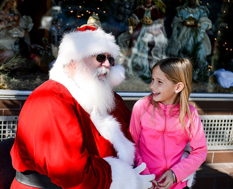 Sophia Shelton, 8, gives Santa Claus her Christmas wishes outside of Busch's Florist, in Jefferson City. Scott Bell, a Santa Claus impersonator, says he loves every minute of being the famous childhood legend. "Look at all the smiles, it's a hoot," he said.