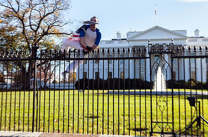 In this photo provided by Vanessa Pena, a man jumps a fence at the White House on Thursday, Nov. 26, 2015, in Washington. The man was immediately apprehended and taken into custody pending criminal charges, the Secret Service said. President Barack Obama and his wife and daughters were spending Thanksgiving the holiday at the White House. (Vanessa Pena via AP)