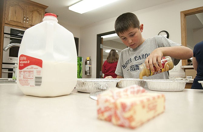 Colton Ketchum, 9, pours gravy into an aluminum container Thursday. The young boy and a dozen others gathered on Thanksgiving to cook meals for the Capitol Police Department, Jefferson City Police Department and Cole County Emergency Medical Services