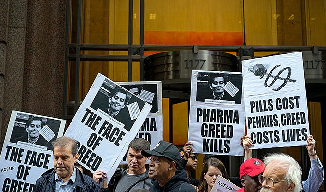 In this Thursday, Oct. 1, 2015, file photo, activists hold signs containing the image of Turing Pharmaceuticals CEO Martin Shkreli in front the building that houses Turing's offices, in New York, during a protest highlighting pharmaceutical drug pricing. After weeks of criticism from patients, doctors and even other drugmakers for hiking a life-saving medicine's price more than fiftyfold, Turing Pharmaceuticals is reneging on its pledge to cut the $750-per-pill price. But a competitor's 99-cent capsule version is selling well.
