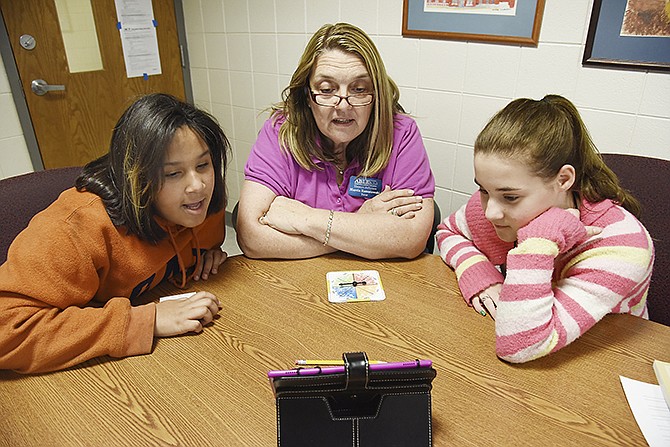 ABLE tutor Marcia Ramatowski, middle, works with sixth-grade students Ivy Jackson, left, and Kaily Frederick as they read "The Bad Beginning," the first in the series "The Series of Unfortunate Events" from the Kindle reader.