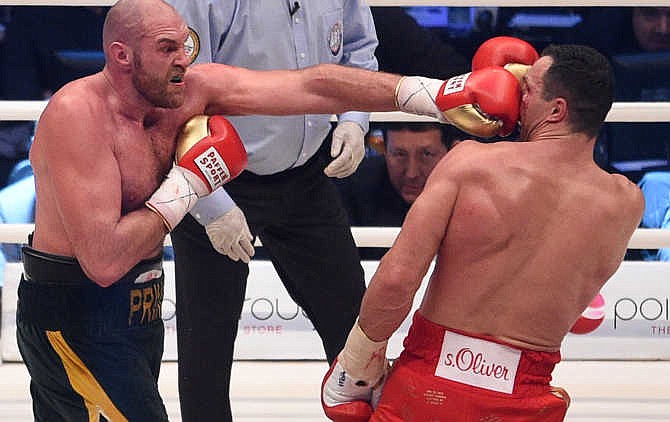 Britain's Tyson Fury, left, punches Ukraine's Wladimir Klitschko and in a world heavyweight title fight for Klitschko's WBA, IBF, WBO and IBO belts in the Esprit Arena in Duesseldorf, western Germany, Saturday, Nov. 28, 2015. 