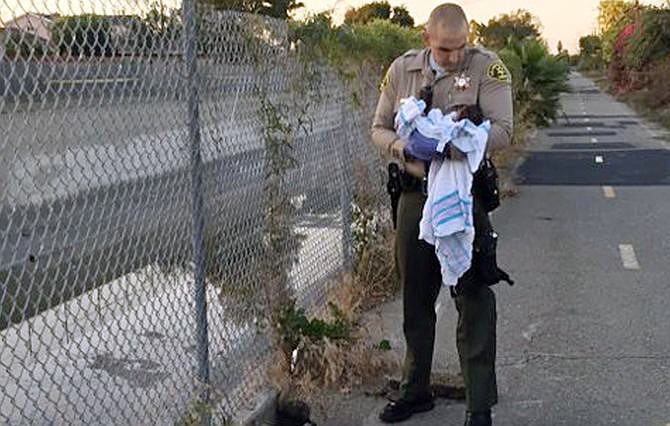 This Friday, Nov. 27, 2015 photo, provided by the Los Angeles County Sheriff's Department shows an unidentified deputy holding an infant girl where she was found abandoned under asphalt and rubble, left, near a bike path in Compton, Calif., as they seek the public's help in identifying her. The baby girl, who was wrapped in a blanket, was believed to be only less than a week old when two deputies found her Friday afternoon. She was taken to a hospital, where she is listed in stable condition.