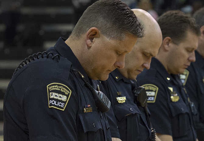 University of Colorado-Colorado Springs police chief Brian McPike, left, stands stands with others officer during a moment of silence for fallen officer Garrett Swasey before a college basketball game Saturday, Nov. 28, 2015, in Colorado Springs, Colo. Swasey was killed in a shooting at a Planned Parenthood Clinic in Colorado Springs on Friday. (Christian Murdock/The Gazette via AP)