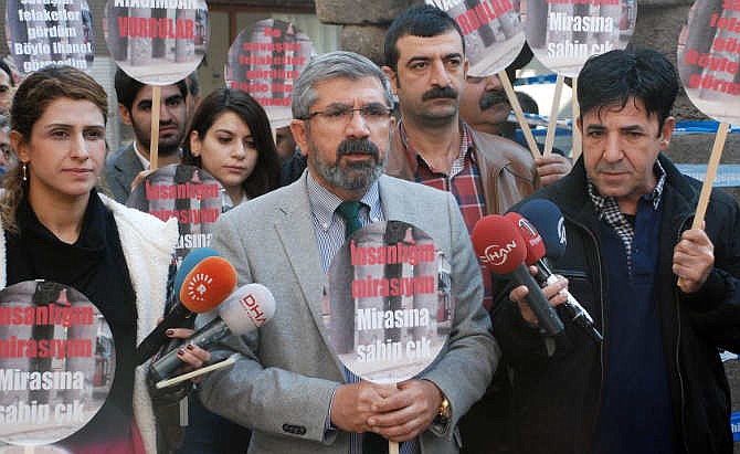 Tahir Elci, the head of Diyarbakir Bar Association, speaks to the media shortly before being killed in Diyarbakir, Turkey, Saturday, Nov. 28, 2015. Elci, a prominent lawyer, who faced a prison term on charges of supporting Turkey's Kurdish rebels, has been killed in an attack in Diyarbakir. Elci was shot on Saturday while he was making a press statement in front of a historical mosques damaged during fightings between Kurdish rebels and security forces. Elci holds a placard that reads: " Let's protect humanity heritage."
