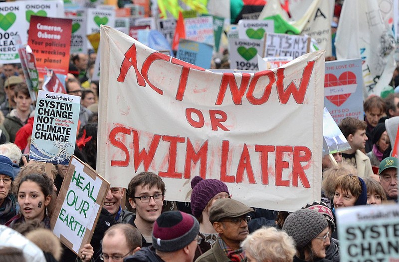 Campaigners hold a banner calling for everybody to act now or swim later, as demonstrators move through the streets of central London, campaigning for ambitious action to tackle climate change on Sunday. Campaigners want the government and other countries to agree on a deal that will shift the world to renewable energy and protect people from the impacts of climate change.