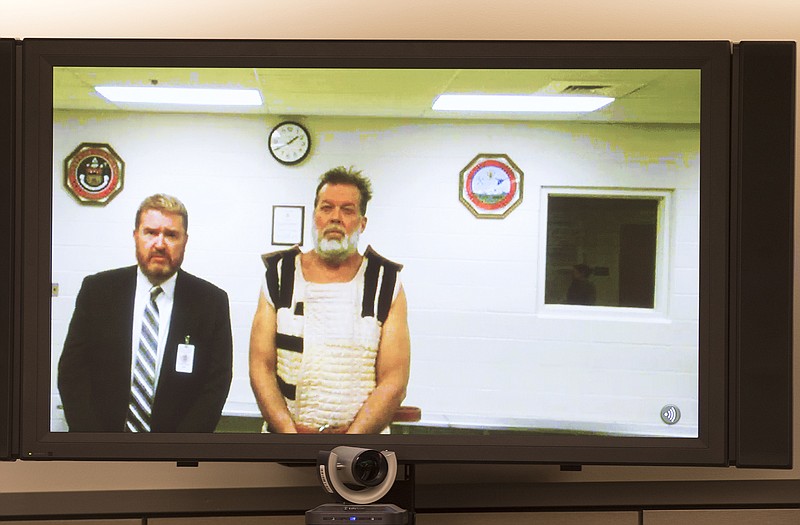 Colorado Springs Planned Parenthood shooting suspect Robert Dear, right, appears via video hearing during his first court appearance, where he was told he faces first-degree murder charges, Monday. At left is public defender Dan King.