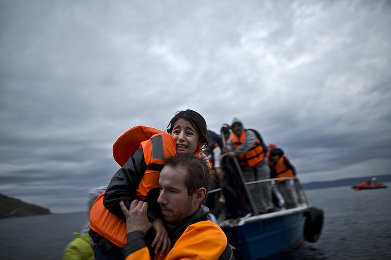 A young refugee girl is carried by a volunteer off a vessel to the shore shortly after arriving with her family from the Turkish coast to the northeastern Greek island of Lesbos, Thursday, Dec. 3, 2015. Greece has been the main point of entry into the European Union for about 700,000 migrants and refugees so far this year. 