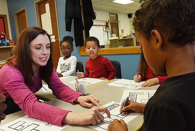 Amauriah Thomas and Conner Abbott, background, watch as Jennifer Penserum helps Z'Kharion Harris learn to write his name during preschool class at Southwest Early Childhood Center in Jefferson City.