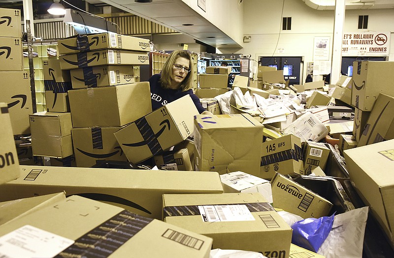 Kelly Byler puts a box in its bin after which the route driver will pick it up and load on his/her vehicle. Byler and several mail processing clerks were working to process mail deliveries in the U.S. Post Office on Jefferson Street Monday morning. Several had been working since 1 a.m. and sorted pallets of packages hauled in by the trailer load. They anticipate the closer to Christmas it gets, the nearer midnight they will arrive to sort last-minute mailings.