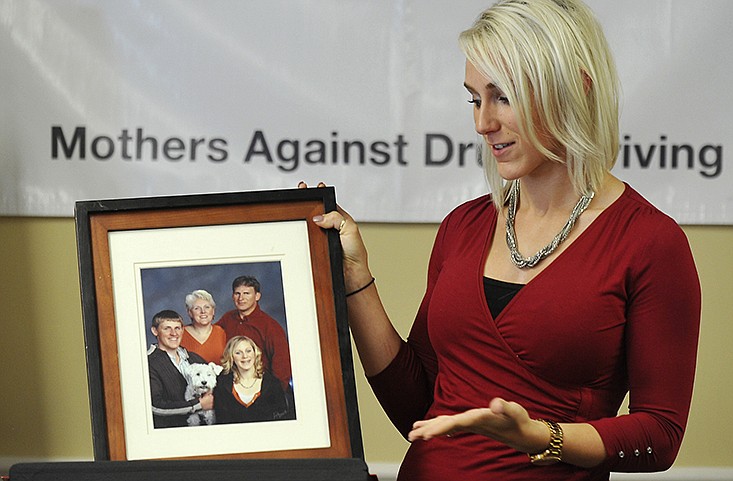 In this photo from December 2015, Johanna Olsen-Henry holds up the last portrait of her family taken before her brother, Tobias (Toby), and mother, Jean, were killed in a wreck caused by an intoxicated driver in November 2007. 
