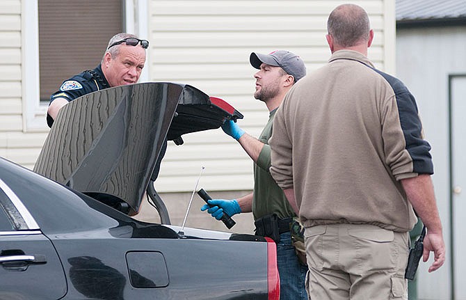 An officer with the Mustang Drug Task Force finishes searching the trunk of a vehicle parked outside a home in Fulton on April 23, 2014. (Fulton Sun file photo)