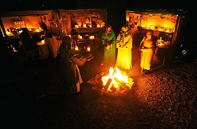 Village shopkeepers use the brief pause between groups to warm themselves by the fire during a 2012 performance of Capital City Christian Church's outdoor Christmas experience "Journey to Bethlehem."