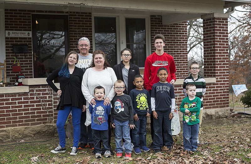 Eric and Heather Gray stand with their family of nine adopted children outside their Jefferson City home.