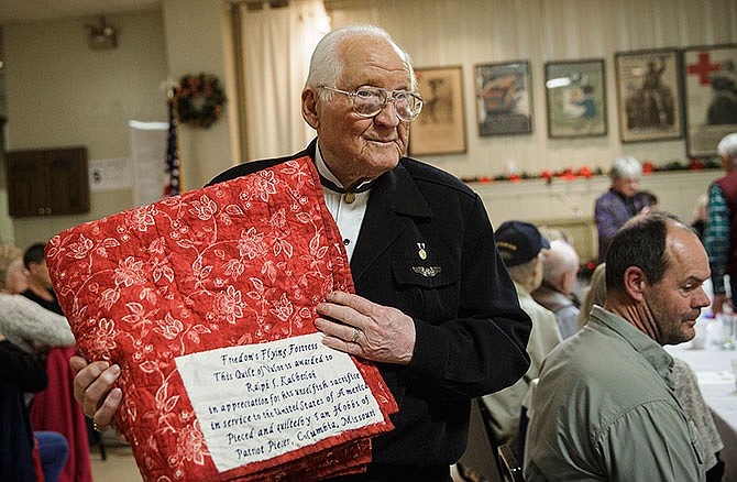Quilts of Valor recipient Ralph Kalberloh holds his quilt
Tuesday evening while walking back to his seat after receiving
his quilt during the American Legion Post 5 Christmas
party.