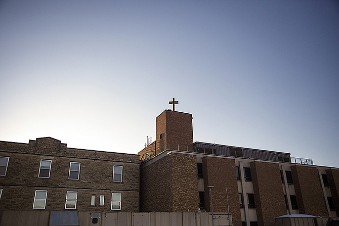Dawn breaks over the cross on top of the old St. Mary's hospital Wednesday morning on what would be the cross' last day atop its iconic perch. Workers from Bee Seen Signs removed the cross which will be given to St. Peter Catholic Church.