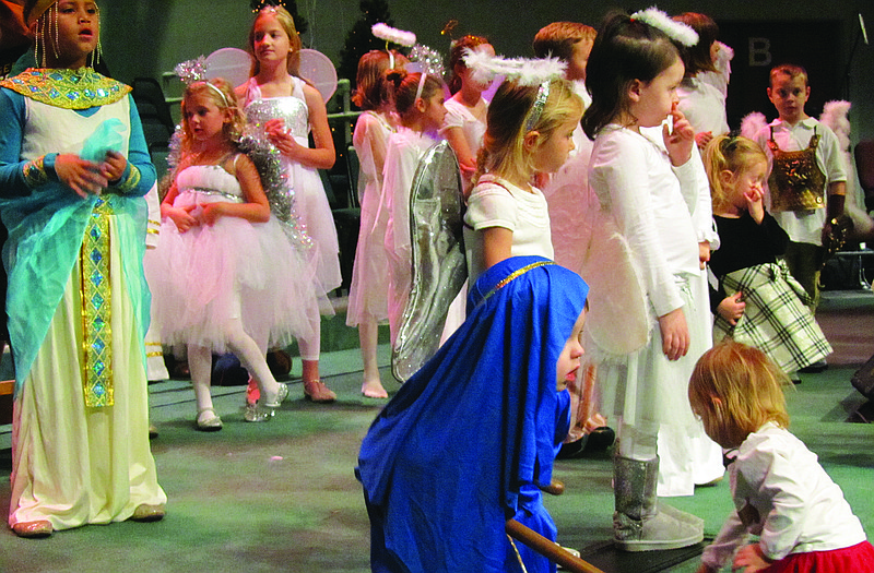 At center, Noah Hawkins, 3, portrays a wise man during Concord Baptist Church's Bathrobe Nativity Service Sunday evening. He was among some 70 children who took part in the simple production. Inset below, Stella Cypress, 5, entertains her 17-month-old sister, Eliana, by waving her dress in Eliana's face while they and other "angels" wait to go on stage.